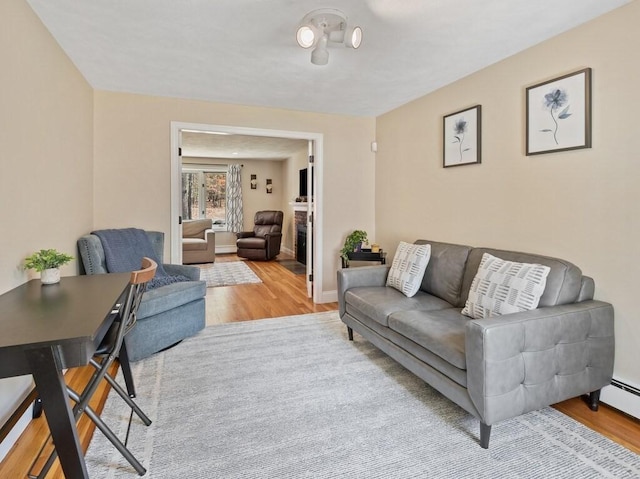 living area with baseboards, wood finished floors, and a baseboard heating unit