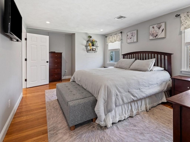 bedroom with wood finished floors, visible vents, recessed lighting, and baseboards