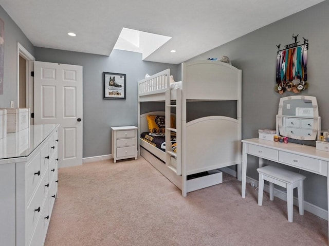 bedroom featuring baseboards, a skylight, and light carpet