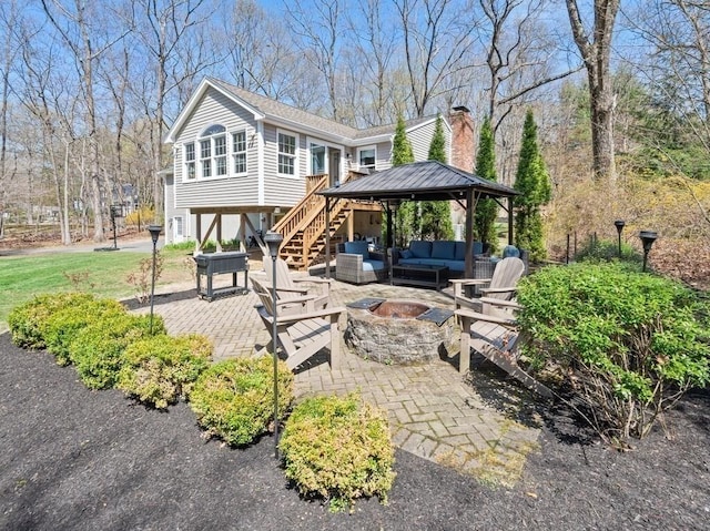 rear view of property with a patio, an outdoor living space with a fire pit, a gazebo, a chimney, and stairway