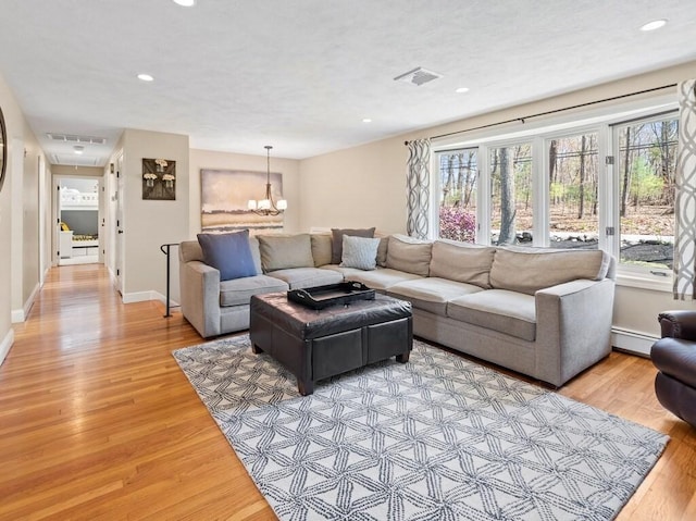 living room with light wood-style floors, recessed lighting, visible vents, and a baseboard heating unit