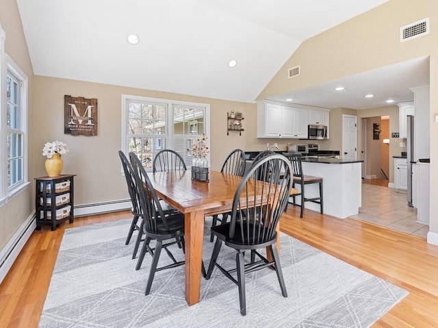 dining area with light wood finished floors, visible vents, and vaulted ceiling
