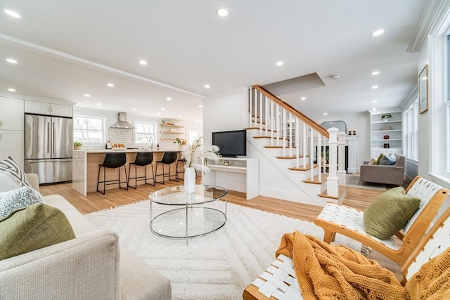 living room featuring crown molding, light wood finished floors, stairway, and recessed lighting