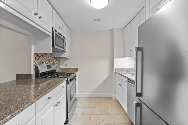 kitchen with dark stone countertops, white cabinets, and stainless steel appliances