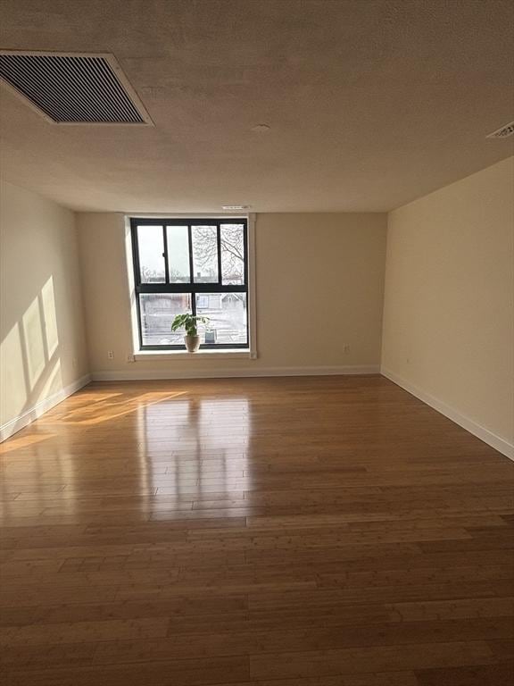 spare room featuring hardwood / wood-style floors and a textured ceiling