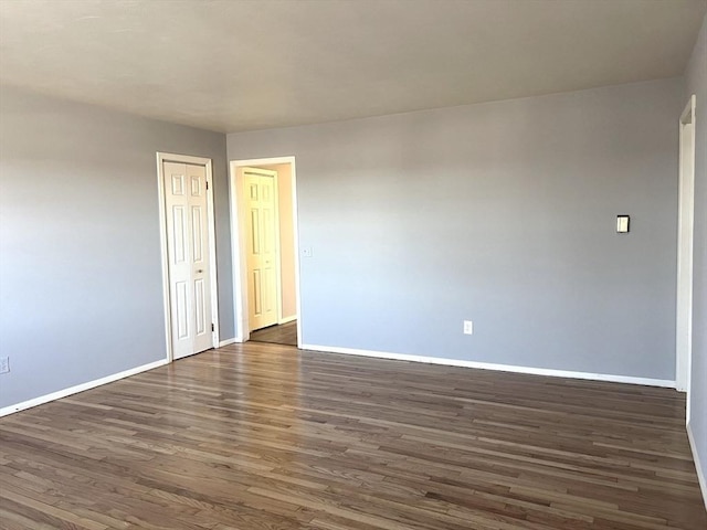 spare room with dark wood-style floors and baseboards