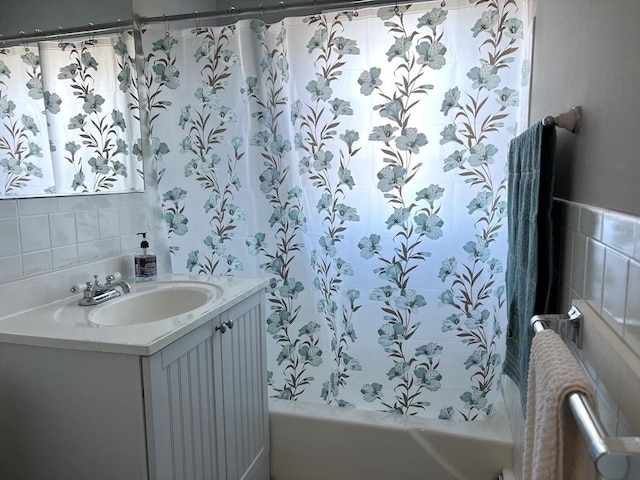 full bathroom with shower / bath combo, vanity, and tile walls