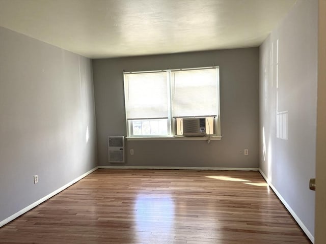 unfurnished room featuring cooling unit, heating unit, baseboards, and wood finished floors