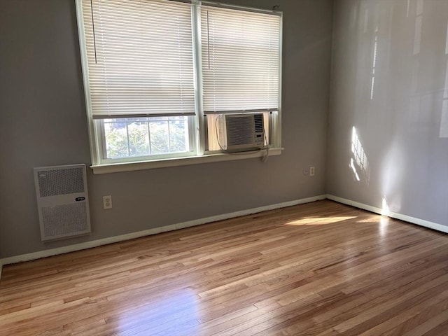 spare room with cooling unit, baseboards, and wood finished floors