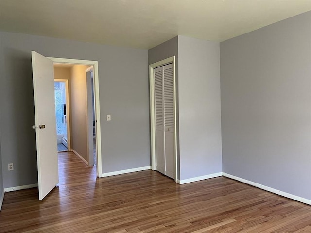 unfurnished bedroom featuring a closet, baseboards, and wood finished floors