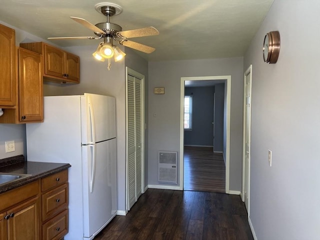 kitchen with dark wood-style floors, baseboards, brown cabinetry, and freestanding refrigerator