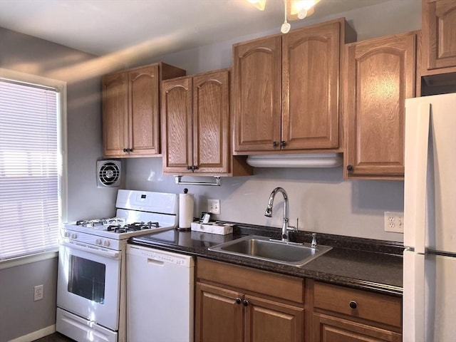 kitchen with white appliances, brown cabinetry, a sink, and visible vents