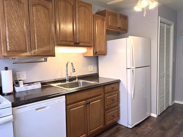 kitchen with white appliances, dark wood finished floors, a sink, and brown cabinetry