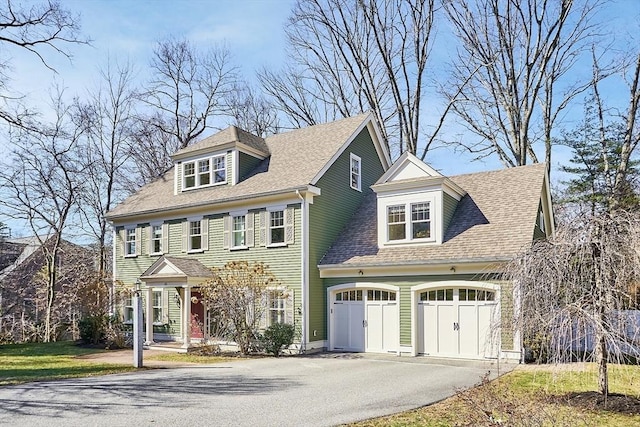 view of front of property featuring driveway, an attached garage, and a shingled roof