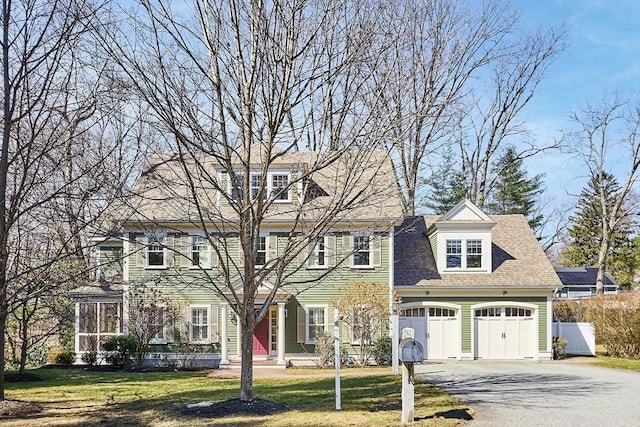 view of front of house with aphalt driveway, fence, a garage, and a front lawn