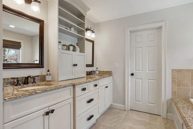 full bathroom with double vanity, a bathing tub, baseboards, and a sink