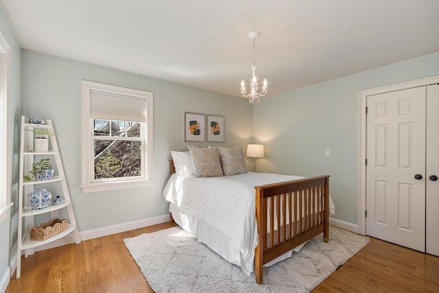 bedroom with a closet, a notable chandelier, baseboards, and wood finished floors