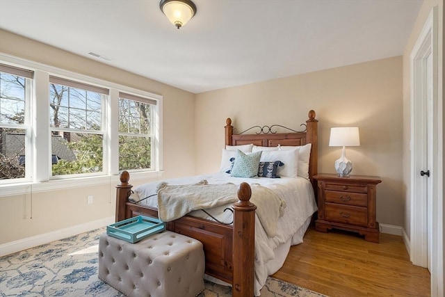 bedroom featuring visible vents, baseboards, and light wood finished floors