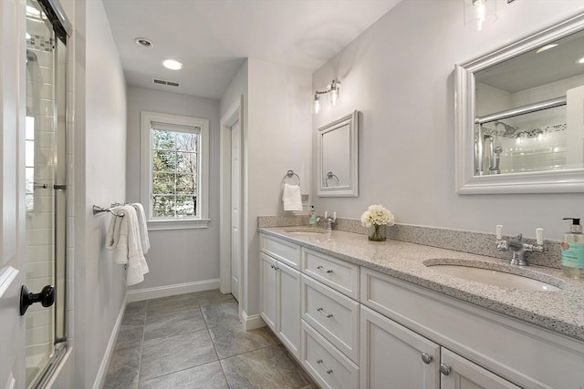 full bath featuring a sink, an enclosed shower, baseboards, and double vanity