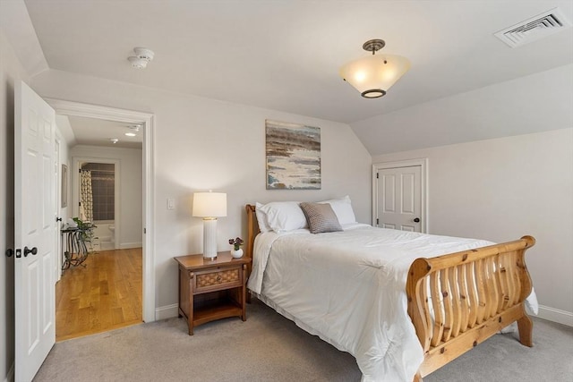 bedroom featuring visible vents, light carpet, baseboards, and vaulted ceiling