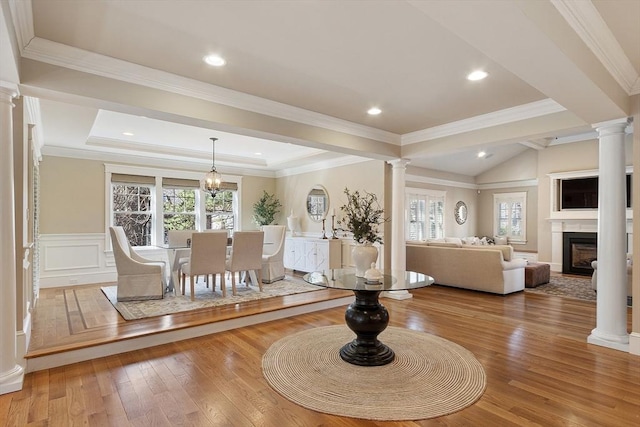 unfurnished living room featuring hardwood / wood-style floors, a fireplace, ornate columns, and wainscoting