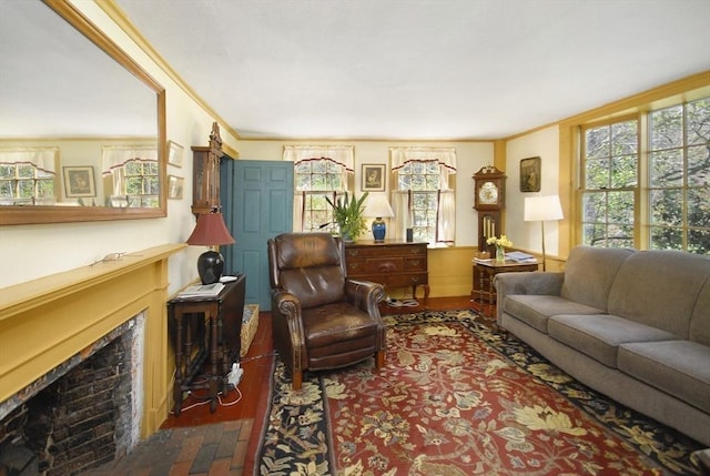 living area with a fireplace with flush hearth, ornamental molding, and a healthy amount of sunlight