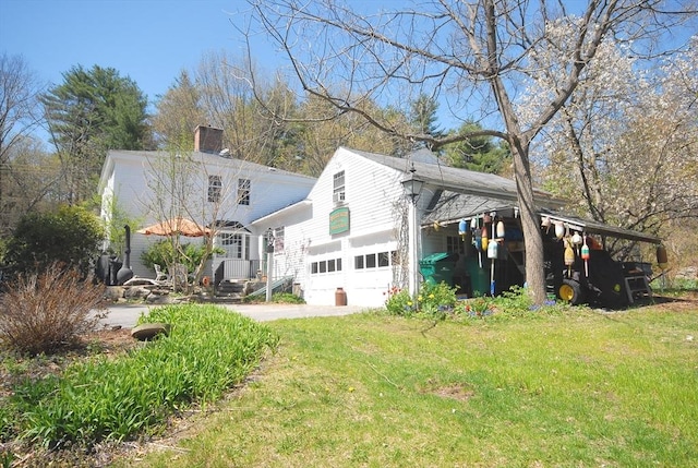 view of property exterior featuring a lawn, a garage, driveway, and a chimney