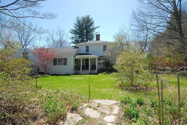 back of house featuring a yard, a chimney, and a sunroom