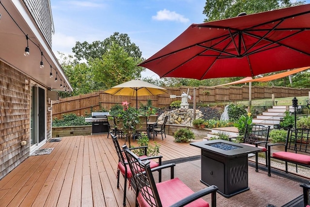 deck with outdoor dining space, an outdoor fire pit, and a fenced backyard