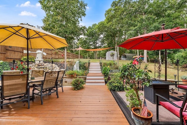 wooden deck with an outbuilding, a shed, outdoor dining area, and fence