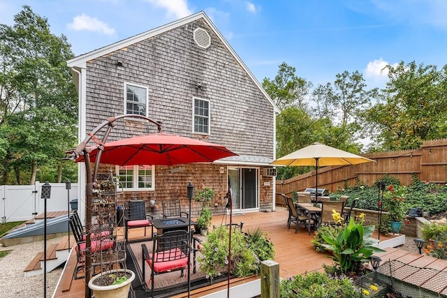 rear view of property featuring outdoor dining space, a gate, a fenced backyard, and a wooden deck