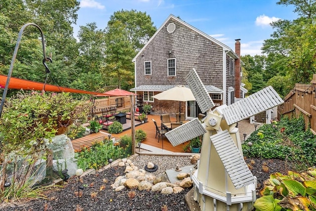 rear view of property featuring a deck, a chimney, and fence