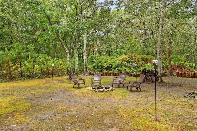 view of yard with an outdoor fire pit and a view of trees