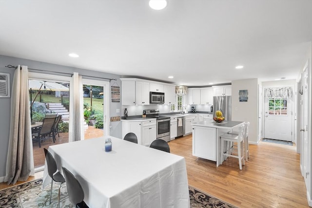 kitchen with plenty of natural light, appliances with stainless steel finishes, light wood-type flooring, and white cabinetry