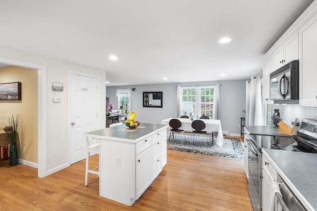 kitchen featuring stainless steel appliances, light wood-type flooring, white cabinets, and a center island