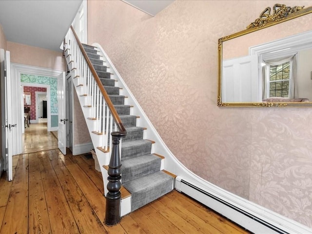 55 Dwight St, Dedham, MA 02026 - staircase featuring baseboard heating, wood-type flooring, and wallpapered walls