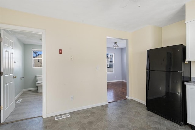 kitchen with white cabinets, black refrigerator, and a chandelier