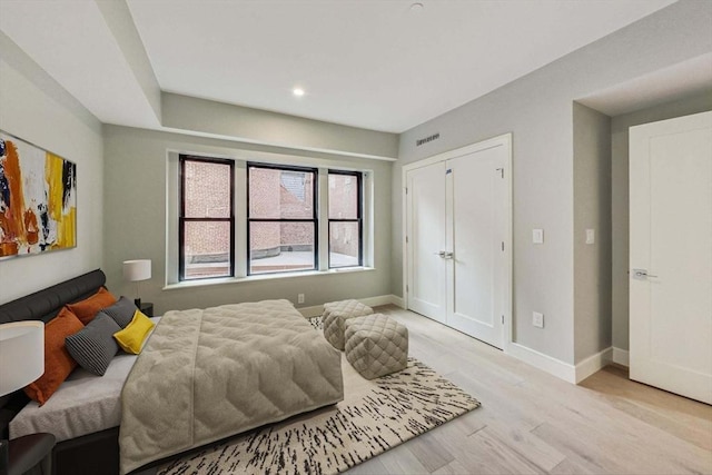 bedroom featuring light wood finished floors, visible vents, and baseboards