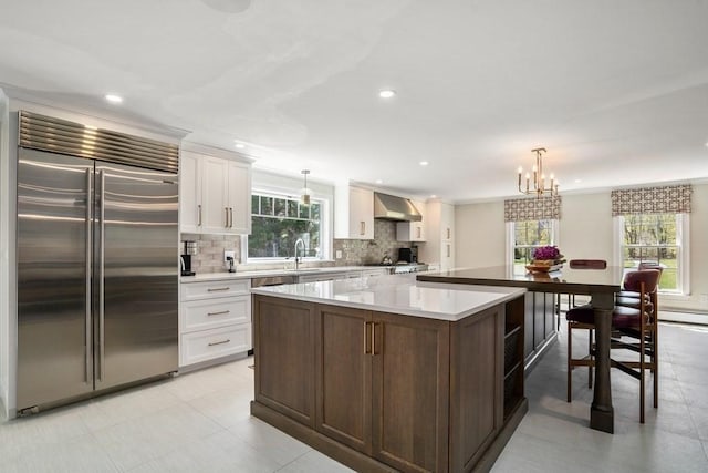 619 Main St, Hanover, MA 02339 - kitchen with built in refrigerator, wall chimney exhaust hood, plenty of natural light, a spacious island, and recessed lighting