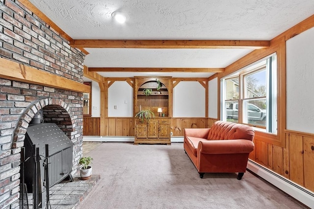 sitting room with wood walls, a textured ceiling, baseboard heating, and beamed ceiling