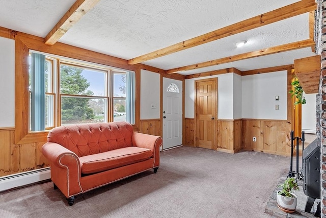 carpeted living room featuring a textured ceiling, beamed ceiling, wood walls, and wainscoting