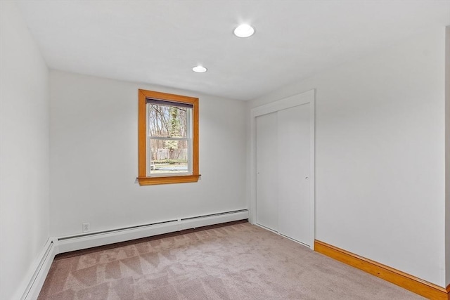 unfurnished bedroom featuring a closet, baseboard heating, carpet flooring, and recessed lighting