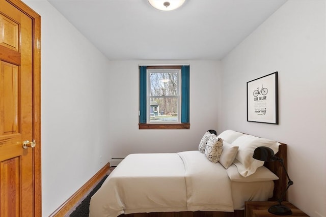 bedroom featuring baseboards, a baseboard heating unit, and wood finished floors