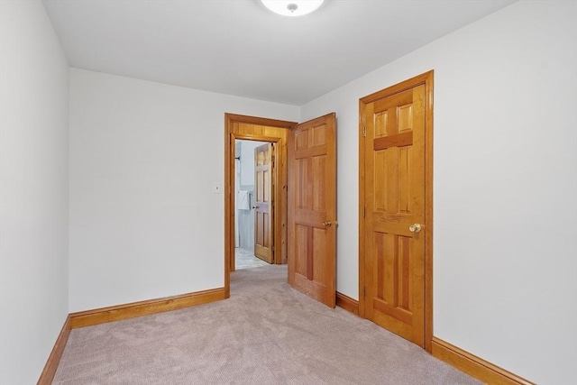 unfurnished room featuring baseboards and light carpet