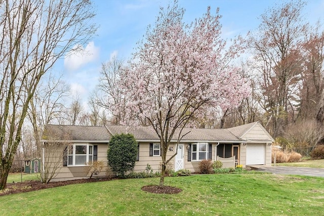 ranch-style house with an attached garage, a front lawn, and aphalt driveway