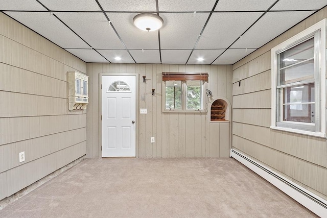 interior space with recessed lighting, wood walls, a drop ceiling, and baseboard heating