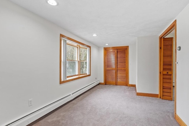 unfurnished bedroom with a closet, baseboards, a baseboard heating unit, and light carpet