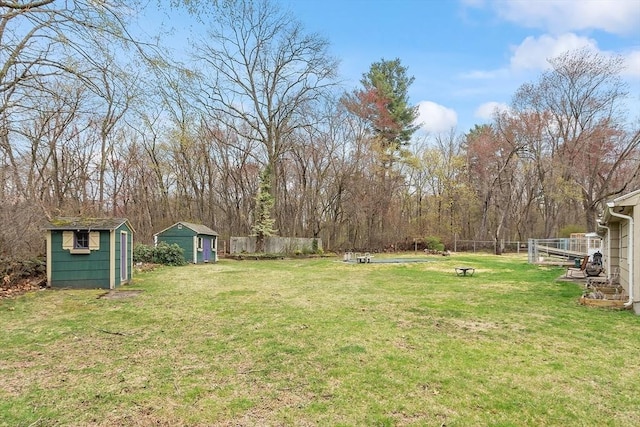 view of yard featuring a storage unit, an outdoor structure, and fence