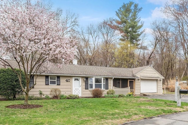 ranch-style home featuring a garage, a front yard, a chimney, a sunroom, and driveway