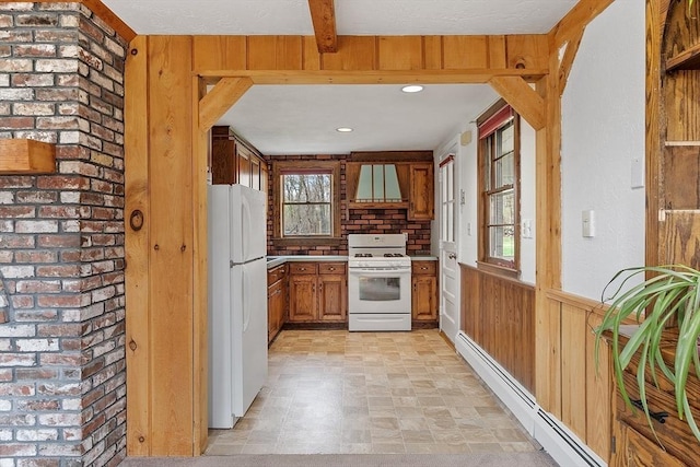 kitchen with a healthy amount of sunlight, brown cabinetry, baseboard heating, and white appliances